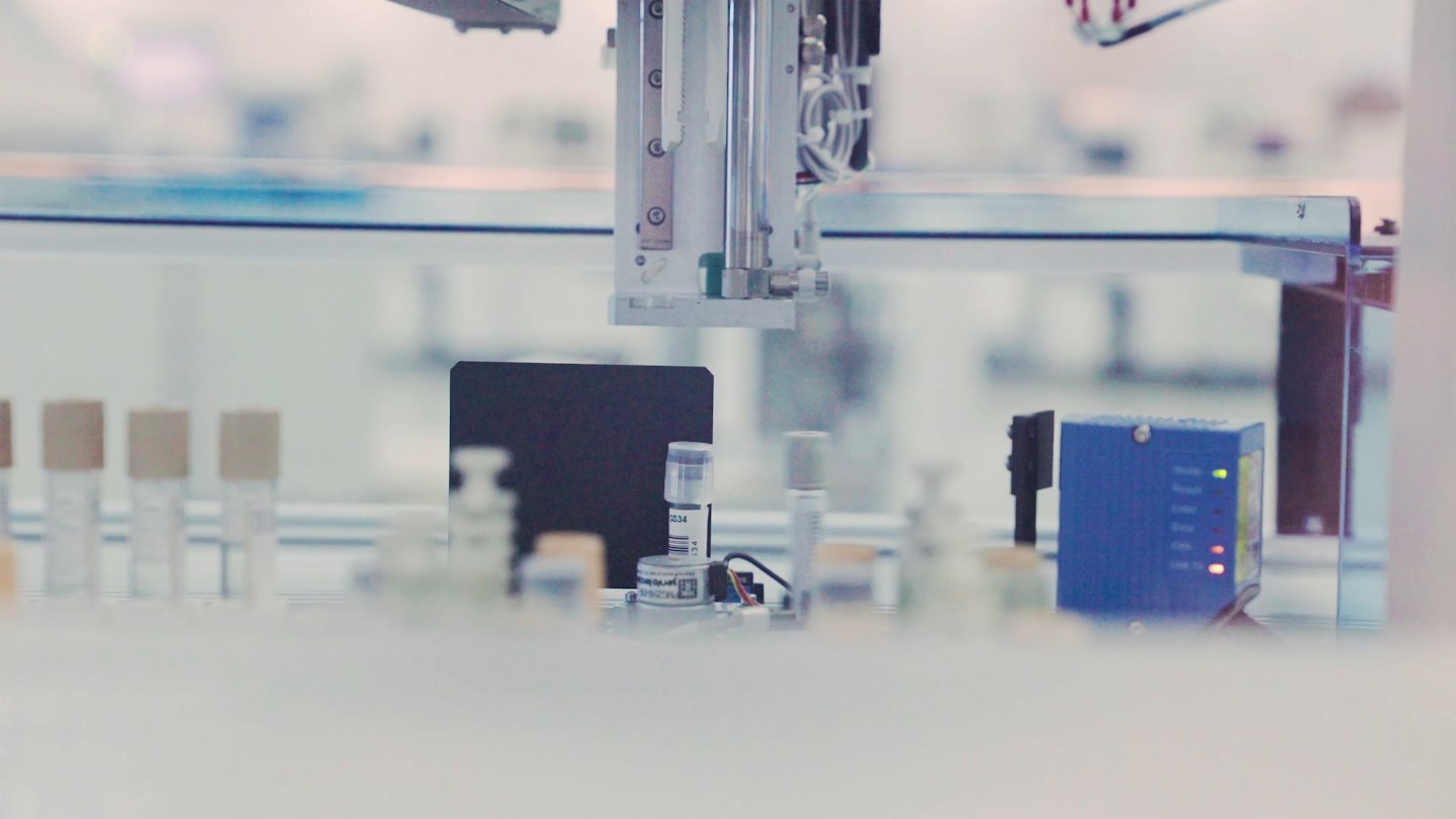 Laboratuvarda deney tüplerinin üzerinde robotik kol.
